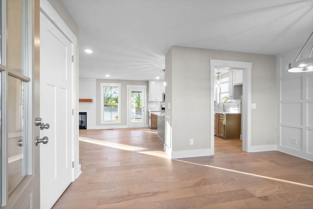 foyer entrance featuring recessed lighting, baseboards, light wood-style floors, and a fireplace