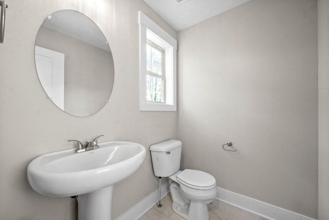 half bath featuring a sink, baseboards, and toilet