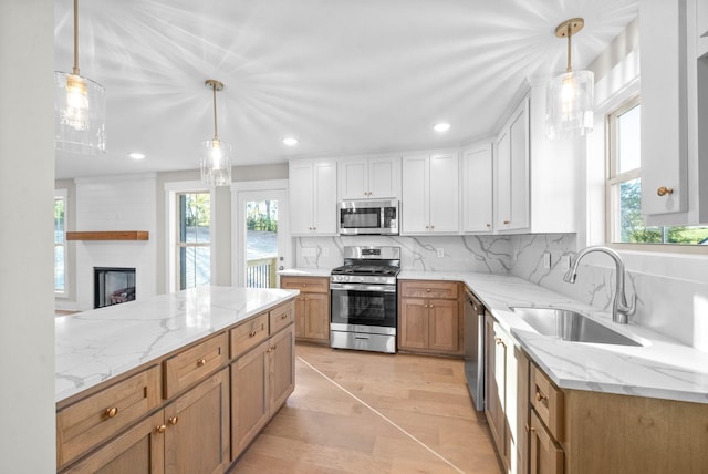 kitchen featuring a sink, light stone counters, backsplash, white cabinetry, and appliances with stainless steel finishes