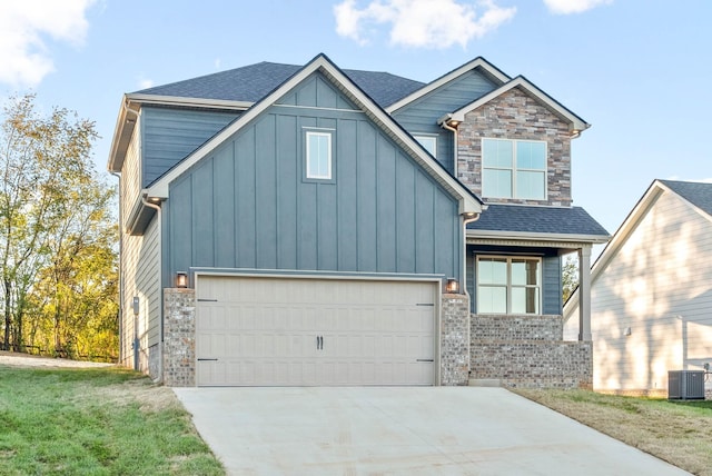 view of front facade featuring board and batten siding, roof with shingles, central AC unit, stone siding, and driveway