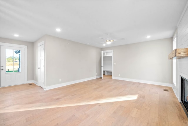 unfurnished living room featuring recessed lighting, a fireplace, baseboards, and light wood-style floors