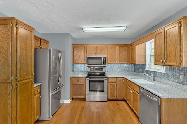 2536 Crescent Meadows Ct, Murfreesboro, TN 37128 - kitchen featuring backsplash, appliances with stainless steel finishes, light wood-style floors, brown cabinetry, and a sink
