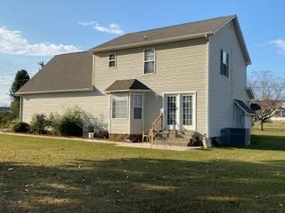 rear view of property with a lawn and cooling unit