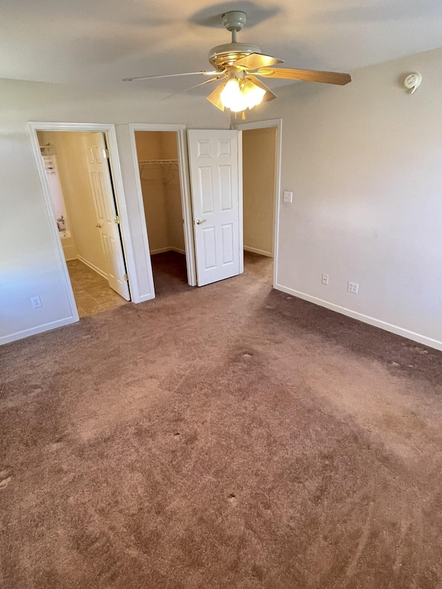 unfurnished bedroom featuring baseboards, carpet floors, ceiling fan, a spacious closet, and a closet