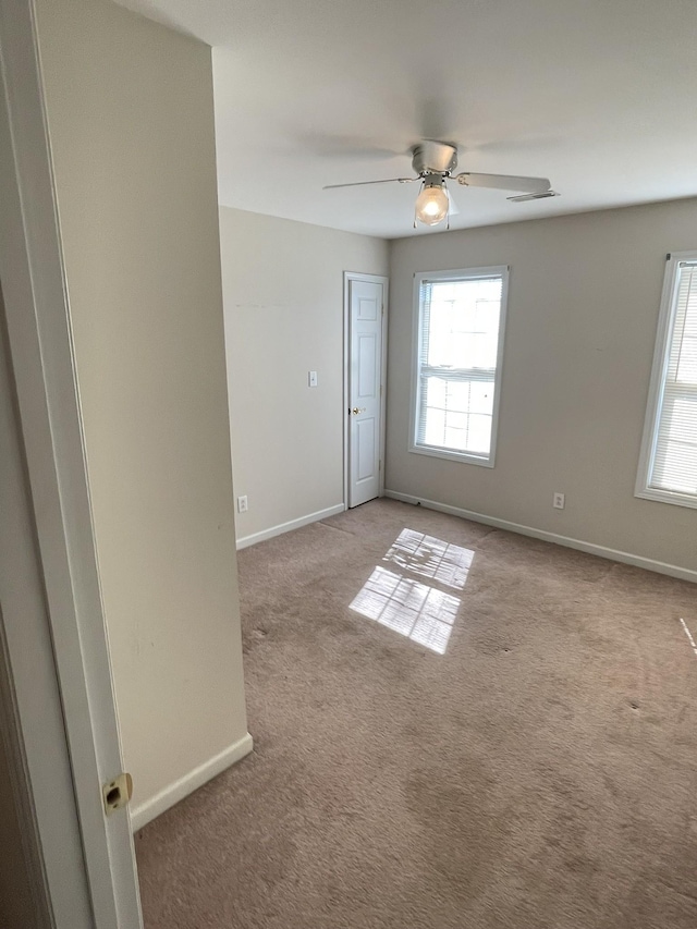 carpeted spare room with baseboards, a healthy amount of sunlight, and ceiling fan