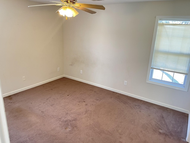 empty room featuring baseboards, dark carpet, and ceiling fan