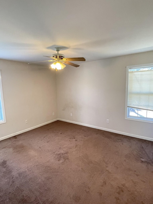 empty room featuring baseboards, ceiling fan, and dark colored carpet