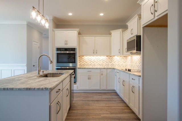 kitchen with a sink, wood finished floors, stainless steel appliances, white cabinets, and crown molding