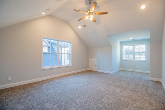 additional living space featuring visible vents, baseboards, ceiling fan, light colored carpet, and vaulted ceiling