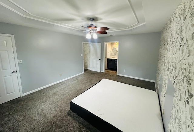 unfurnished bedroom with ceiling fan, baseboards, dark colored carpet, and connected bathroom