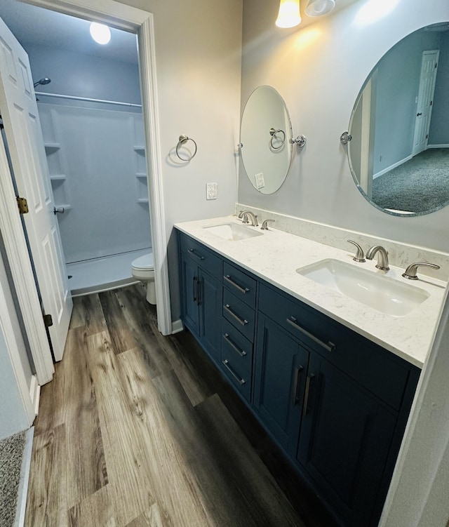 bathroom with a sink, toilet, wood finished floors, and double vanity