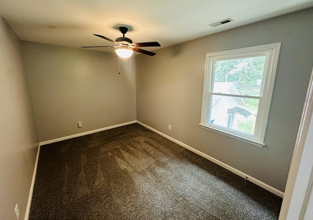 unfurnished room featuring dark colored carpet, visible vents, plenty of natural light, and baseboards