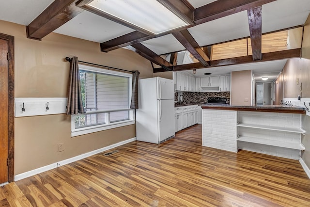 kitchen with open shelves, freestanding refrigerator, decorative backsplash, dark countertops, and light wood-type flooring