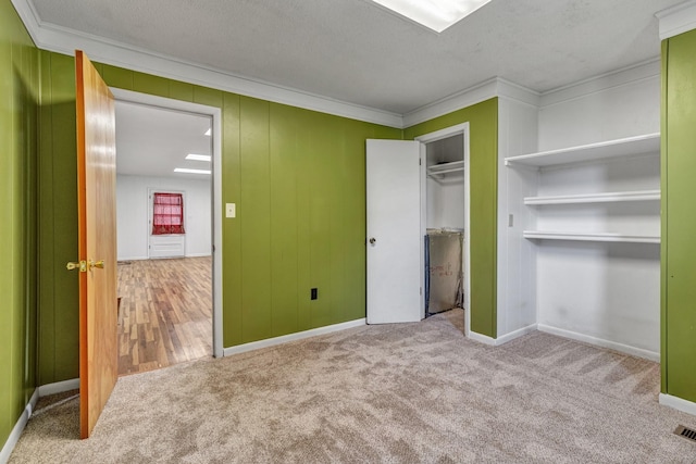 unfurnished bedroom with carpet flooring, a textured ceiling, visible vents, and ornamental molding