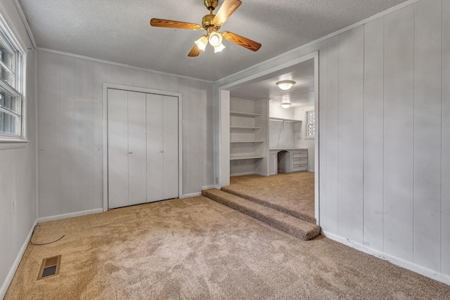 unfurnished bedroom with a textured ceiling, carpet, visible vents, and ornamental molding