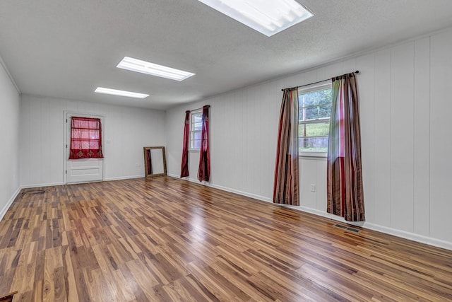 empty room with visible vents, baseboards, a textured ceiling, and wood finished floors