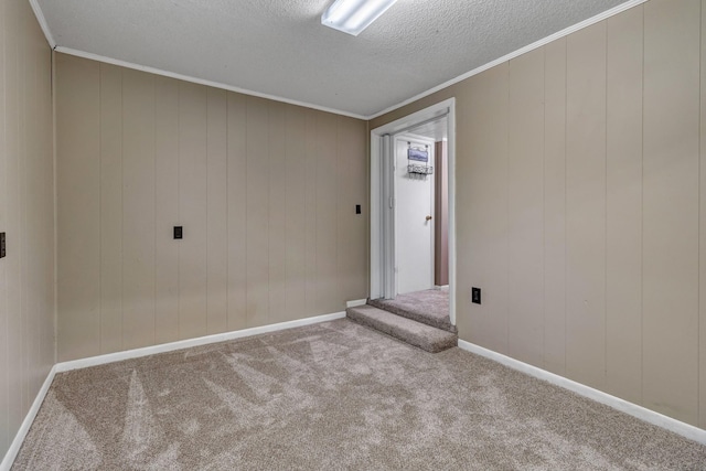 spare room featuring carpet, baseboards, ornamental molding, stairs, and a textured ceiling