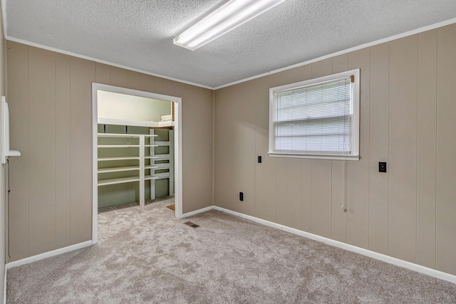 carpeted empty room featuring baseboards, a textured ceiling, and crown molding