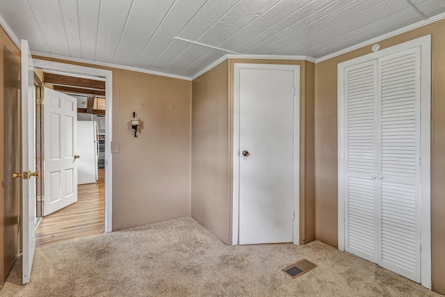 unfurnished bedroom with visible vents, ornamental molding, carpet floors, freestanding refrigerator, and a closet