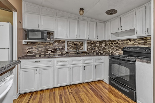 kitchen featuring black appliances, a sink, light wood-style floors, white cabinets, and decorative backsplash