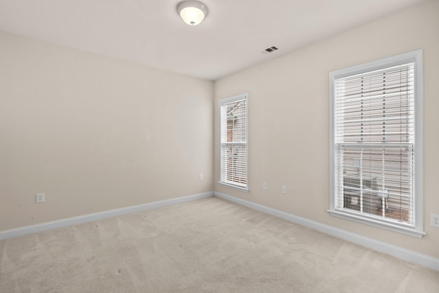 unfurnished room featuring baseboards, visible vents, and light carpet