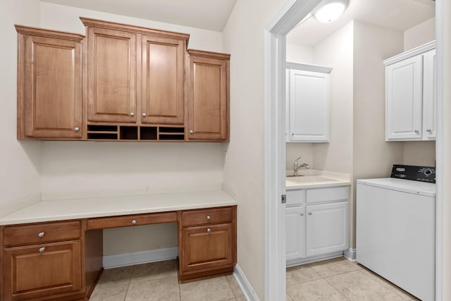 laundry area with a sink, washer / clothes dryer, cabinet space, light tile patterned floors, and baseboards