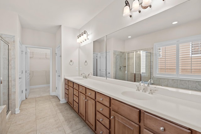 bathroom featuring double vanity, a stall shower, a spacious closet, and a sink