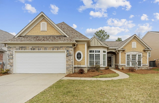 view of front of house featuring a shingled roof, a front lawn, central air condition unit, a garage, and stone siding