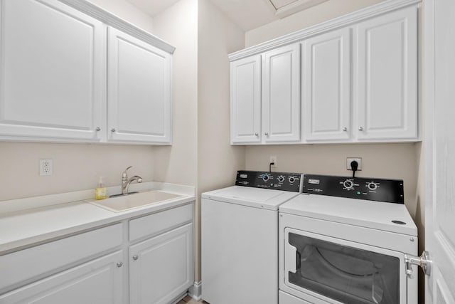 clothes washing area with cabinet space, washer and dryer, and a sink