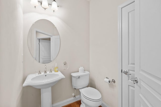 bathroom with baseboards, toilet, and wood finished floors