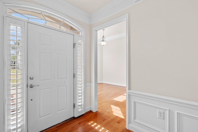 foyer with ornamental molding and wood finished floors