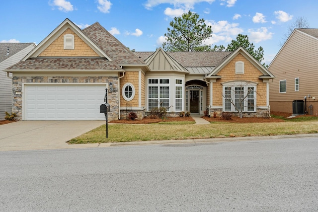 view of front of property with driveway, stone siding, central AC, roof with shingles, and an attached garage