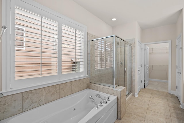 full bathroom featuring a spacious closet, plenty of natural light, a shower stall, and a tub with jets