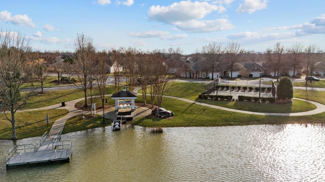 view of community with a yard, a water view, and a boat dock