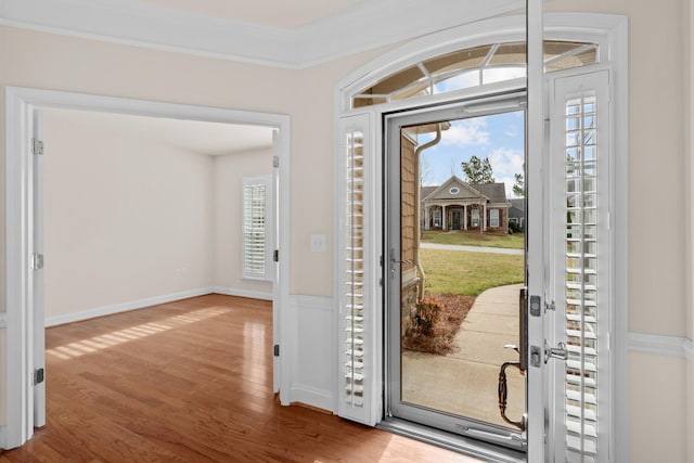 foyer entrance featuring crown molding, wood finished floors, and baseboards