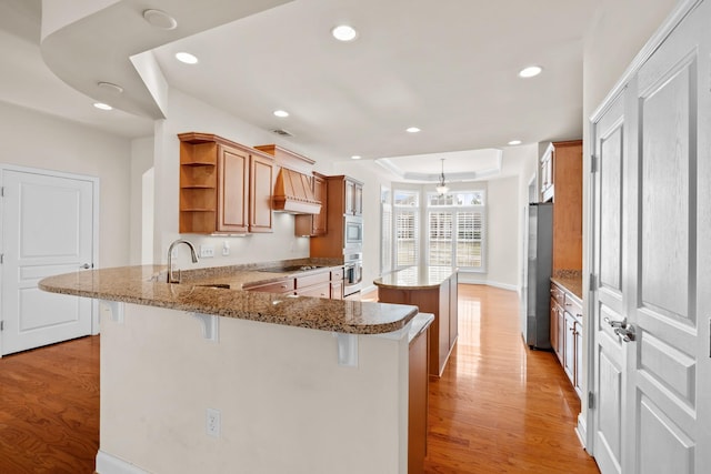 kitchen with light wood-style flooring, open shelves, a sink, a center island, and stainless steel appliances