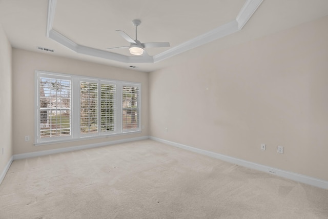 carpeted empty room with baseboards, visible vents, ceiling fan, ornamental molding, and a raised ceiling