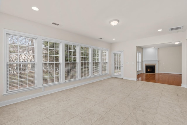 unfurnished living room featuring recessed lighting, visible vents, baseboards, and a warm lit fireplace