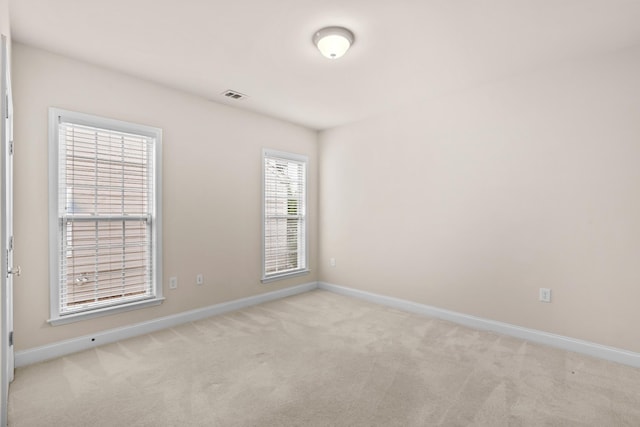 carpeted spare room with visible vents and baseboards