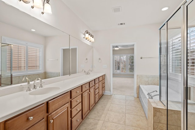 bathroom featuring tile patterned flooring, double vanity, a bath, and a sink