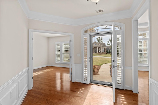 foyer with wainscoting, ornamental molding, and wood finished floors