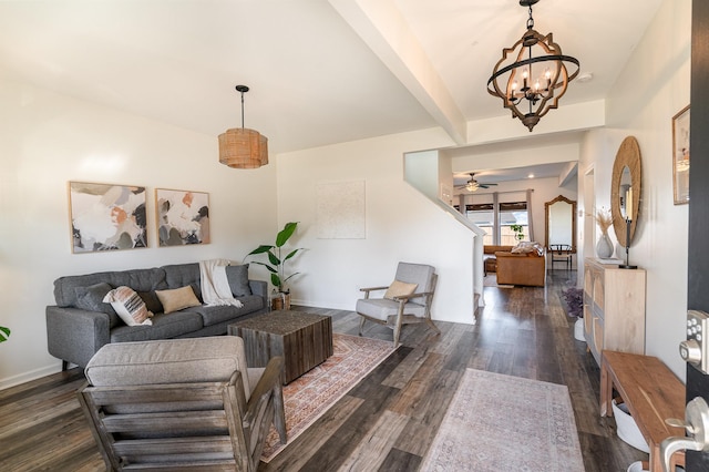 living room with ceiling fan with notable chandelier, beam ceiling, baseboards, and dark wood-style flooring