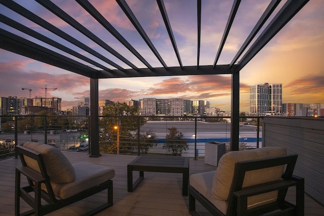 balcony at dusk featuring a city view and a pergola