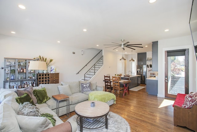 living room with a ceiling fan, stairway, recessed lighting, and wood finished floors