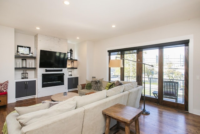 living room featuring recessed lighting, a large fireplace, dark wood-type flooring, and a healthy amount of sunlight