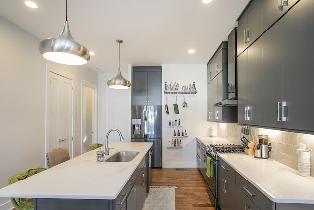 kitchen featuring backsplash, dark wood-type flooring, a center island with sink, stainless steel appliances, and a sink