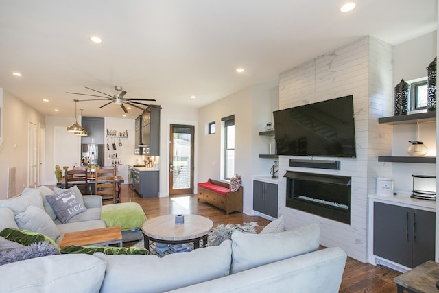 living room with dark wood-style floors, recessed lighting, a large fireplace, and ceiling fan