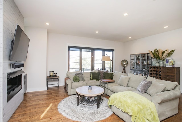 living room featuring light wood finished floors, recessed lighting, and a large fireplace