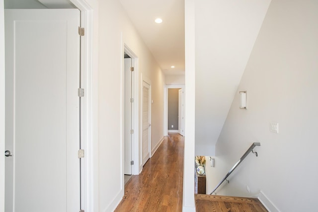 hall with an upstairs landing, recessed lighting, light wood finished floors, and baseboards