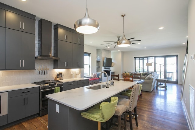 kitchen featuring a healthy amount of sunlight, wall chimney range hood, double oven range, and a sink